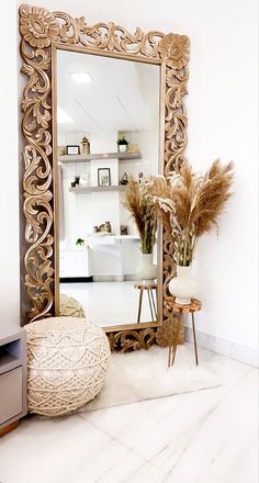 a large mirror sitting on top of a white floor next to a vase filled with flowers