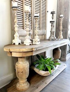 a wooden table with candles on it and a potted plant next to it in front of shutters