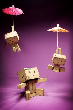 two cardboard figures with umbrellas attached to them