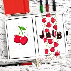 an open notebook with cherries and the word joy written in black ink on it