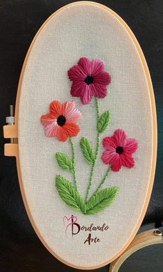 three pink and red flowers on a white embroidery