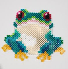 a frog made out of plastic beads sitting on top of a table