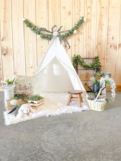 a white teepee tent sitting on top of a floor next to potted plants