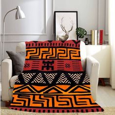 an orange and black blanket sitting on top of a couch next to a white chair