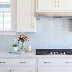 a kitchen with white cabinets and blue backsplash tiles on the wall behind the stove