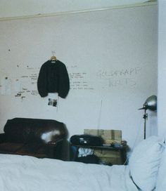 a bedroom with a bed, chair and coat hanging on the wall