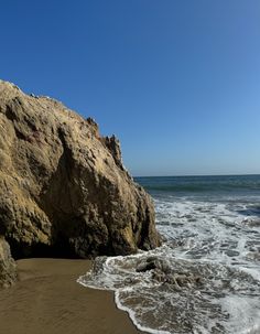 a person standing on the beach next to some rocks