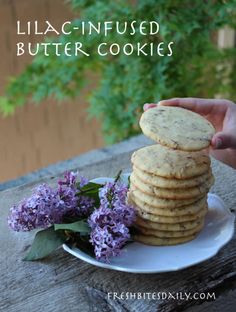 a stack of cookies sitting on top of a white plate next to purple lila flowers