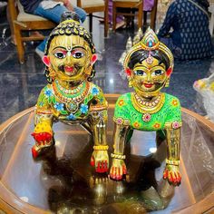 two colorfully painted wooden statues sitting on top of a glass table next to each other