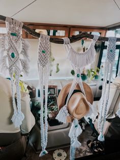 hats hanging from the ceiling in front of a window with other items on it and another item behind them