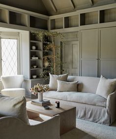 a living room filled with white furniture and lots of books on top of a table