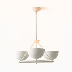 three white bowls hanging from a light fixture