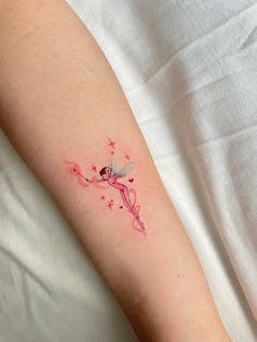 a small tattoo on the arm of a woman with a pink flower in her hand