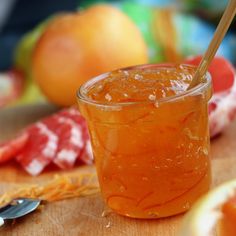 a glass filled with orange juice sitting on top of a cutting board