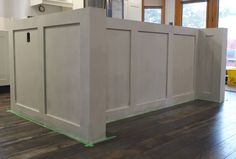 an unfinished kitchen island in the middle of a room with hard wood floors and white cabinets