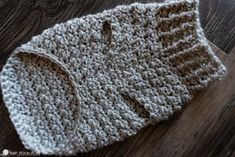 two crocheted hats sitting on top of a wooden table