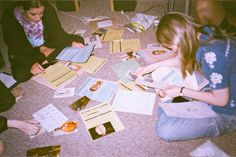 several people sitting on the floor looking at some papers and envelopes that have been placed around them