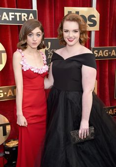 two women standing next to each other on a red carpet