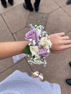 a bouquet of flowers is being held by someone's hand on the sidewalk with other people