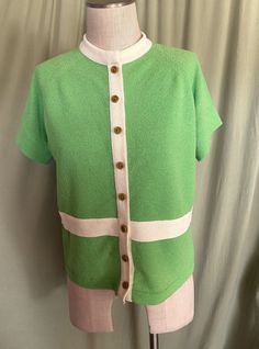 a green and white sweater on a mannequin's dummy with a light pink shirt underneath it