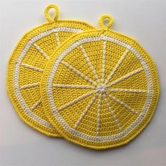 two yellow crocheted coasters sitting next to each other on a white surface