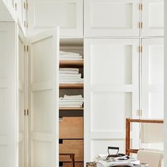 an open closet with clothes and other items on the floor in front of white cupboards