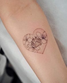 a heart shaped tattoo with paw prints on the inside of it's left arm