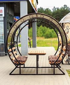 two wooden chairs sitting on top of a table in front of a metal circular structure