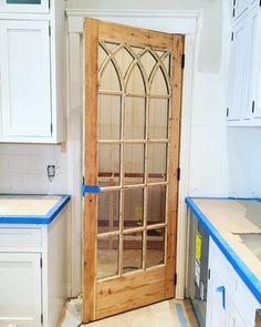 an unfinished kitchen with white cabinets and blue tape on the counter tops, and a wooden door