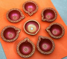 six pink and gold dishes sitting on top of an orange paper towel with flowers in the center