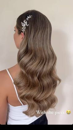 the back of a woman's head with long, wavy hair and flowers in her hair