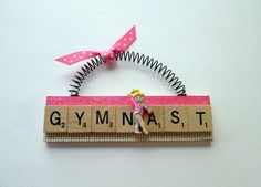 a piece of wood with the word gymnastics on it and a doll hanging from it