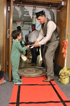 a man handing something to a little boy in front of a door with other people