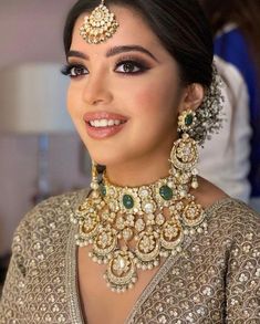 a woman wearing a gold and green necklace with matching earring set on her head