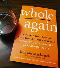 an orange book sitting on top of a wooden table next to a pair of glasses