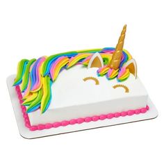 a white cake with a rainbow colored unicorn horn on top