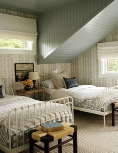 two beds in a room with white walls and carpeted flooring, along with windows