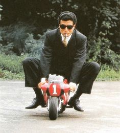 a man riding on the back of a red motorcycle