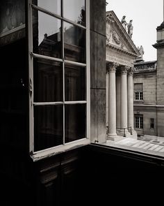 an old building with columns and windows in front of it, looking out onto the street