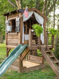 a tree house with a slide in the yard