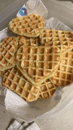 four waffles are stacked on top of each other in a glass bowl with napkins