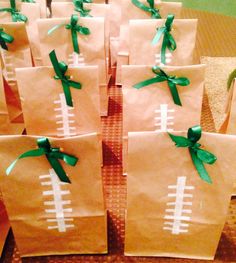 brown paper bags with green bows and footballs on them are sitting on a table