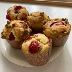 several muffins on a white plate with raspberries