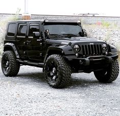 a black jeep is parked in the gravel