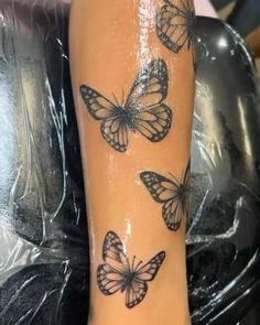 a woman's arm with three butterflies on it and one is showing off her tattoo