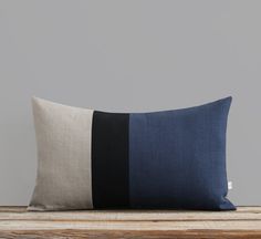 a black and white pillow on top of a wooden table next to a gray wall