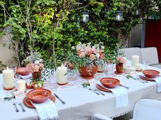 a table set with plates, candles and flowers