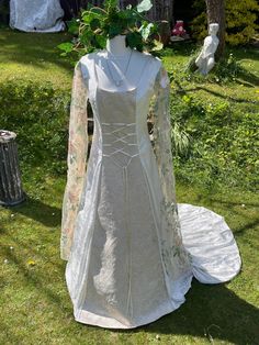 a white wedding dress on display in the grass