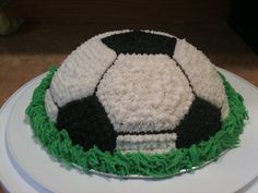 a soccer ball cake sitting on top of a white plate with green and black frosting