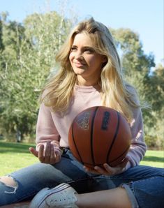 a woman sitting on the ground holding a basketball